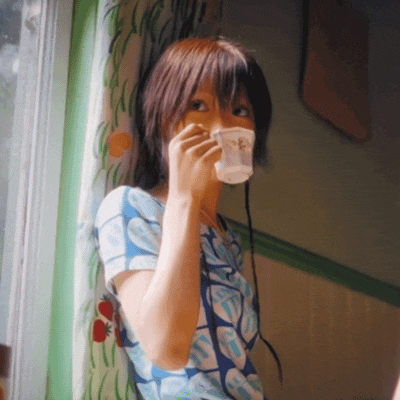 a woman in a blue and white floral shirt drinks from a cup