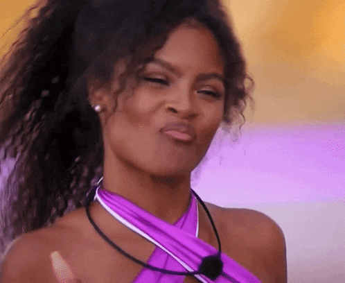 a woman with curly hair is wearing a purple top and making a face