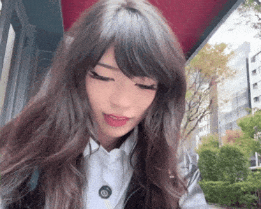 a woman with long brown hair and a white shirt has a button on her shirt that says ' a ' on it