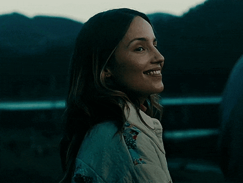 a woman with long dark hair is smiling in a dark room