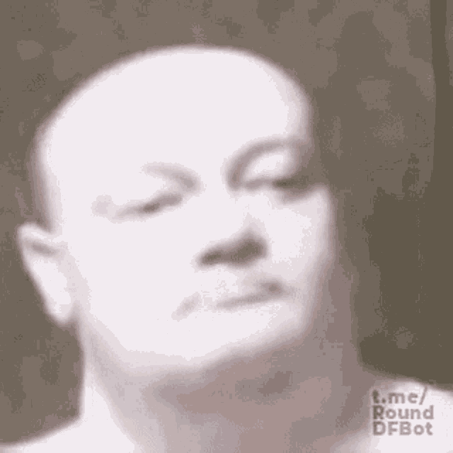 a close up of a man 's face with his eyes closed and a bald head .