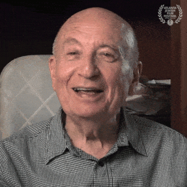 an older man is smiling in front of an atlanta international film festival laurel