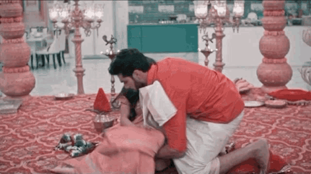 a man in a red shirt is kneeling down next to a woman in a pink dress