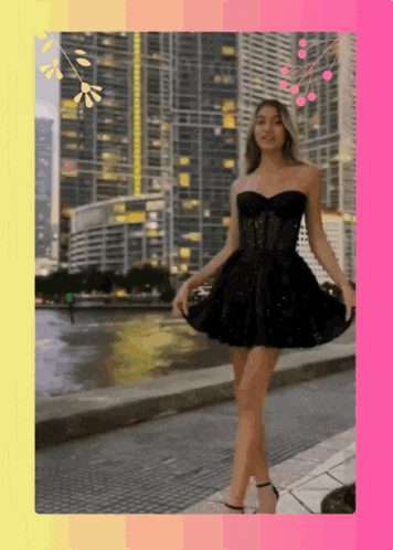 a woman in a black dress is walking down a sidewalk