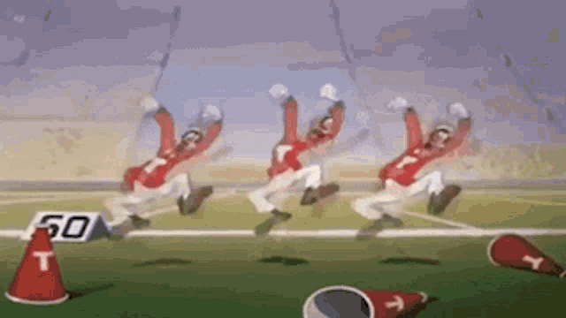 a group of football players are running on a field with cones and a sign that says 50 .