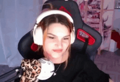 a woman is wearing headphones and holding a stuffed animal while sitting in a chair .