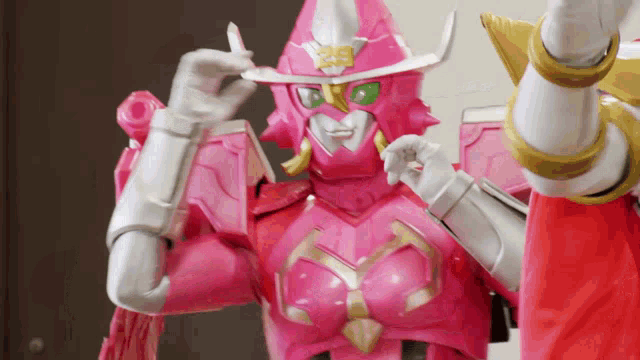 a pink robot with green eyes and a white hat