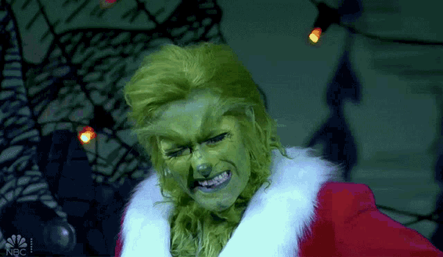 a woman dressed as the grinch is making a funny face