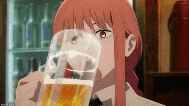 a girl with long red hair is drinking a glass of beer from a glass