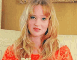 a woman in a red dress is sitting on a couch holding a bowl of popcorn .