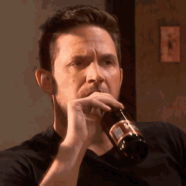 a man in a black shirt drinks from a bottle with a label that says du