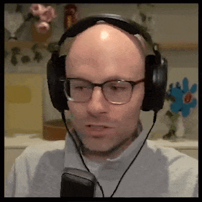 a bald man wearing glasses and headphones is looking at the camera .