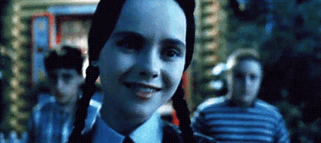 a girl with pigtails is smiling in front of a group of people in a dark room .