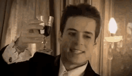 a man in a suit and bow tie is holding a glass of wine .