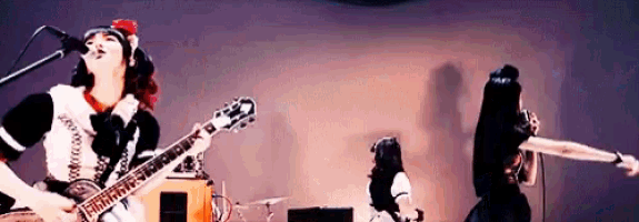 a woman is playing a guitar while another woman sings into a microphone