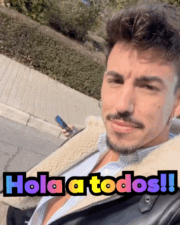 a man with a beard is wearing a jacket with the words hola a todos written on it