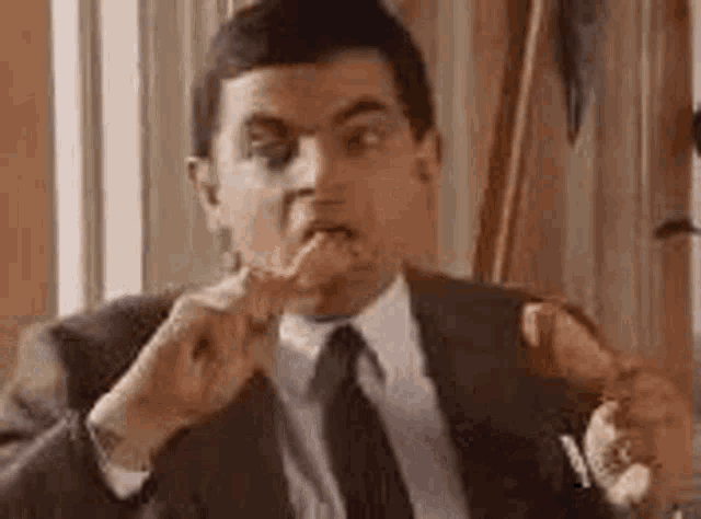a man in a suit and tie is eating a french fry .