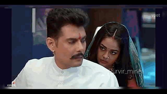 a man with a mustache and a woman with a nose ring are looking at each other .