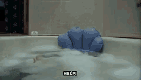 a person is taking a bath in a bathtub with a blue pillow in it .