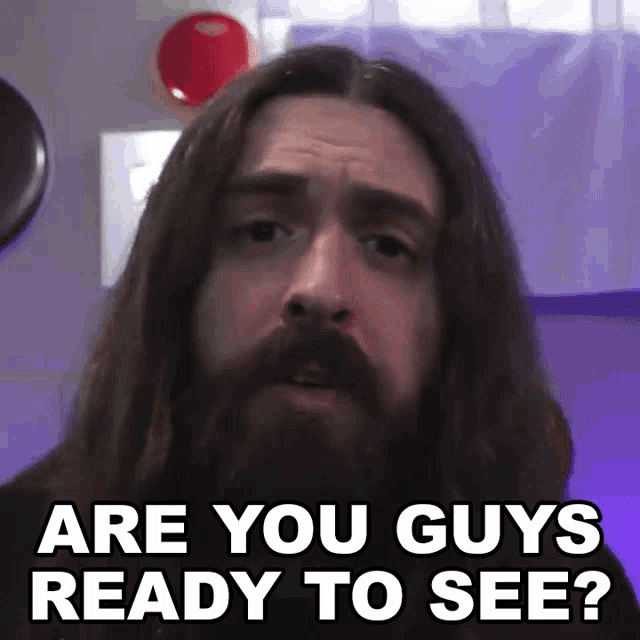 a man with long hair and a beard is asking are you guys ready to see ?