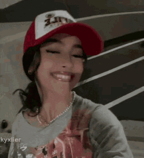 a girl wearing a red hat and a necklace is smiling .
