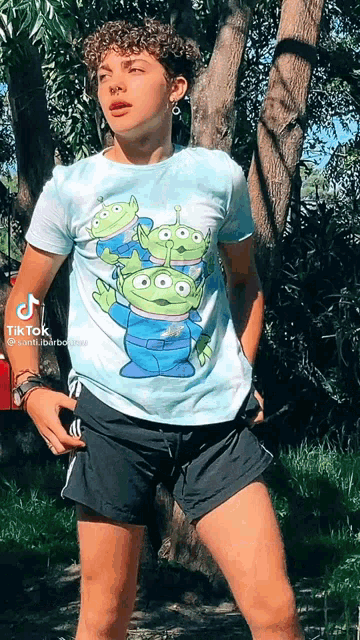 a young man wearing a toy story alien t-shirt and black shorts