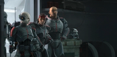 a group of men in armor are standing next to each other in a dark room .