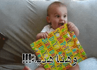 a baby is holding a birthday present with arabic writing