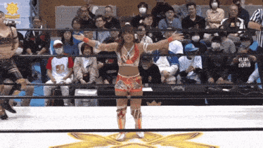 a woman in a wrestling ring stands in front of a crowd wearing a hijab bomb shirt