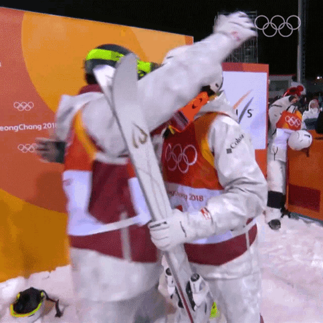 two skiers are hugging each other in front of a pyeongchang 2018 sign