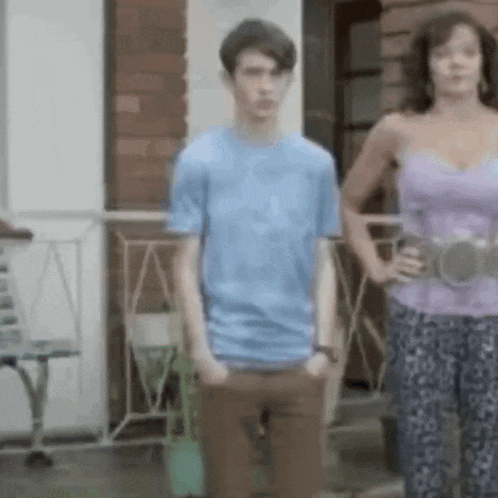 a man in a blue shirt and a woman in a purple top are standing on a porch .