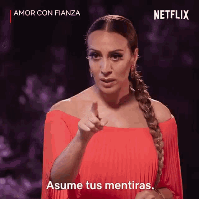 a woman in a red dress is pointing at the camera and says assume tus mentiras