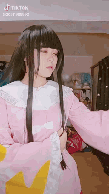 a girl with long black hair is wearing a pink kimono