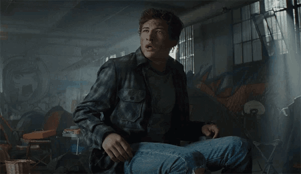 a man in a plaid shirt is sitting on the floor