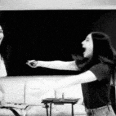 a black and white photo of two women standing in front of a chalkboard