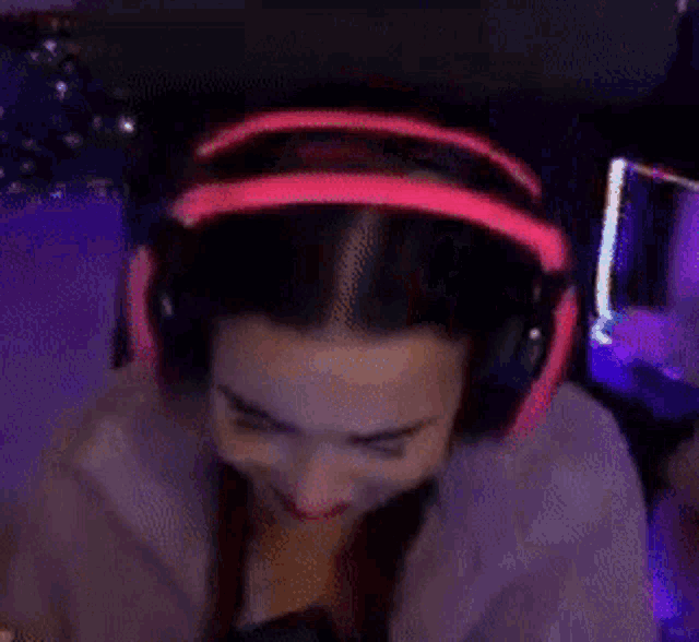 a woman wearing pink headphones is covering her face .