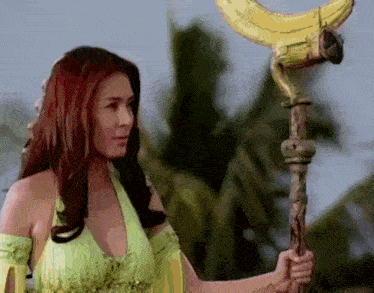 a woman in a green top is holding a yellow object with a crescent moon on it