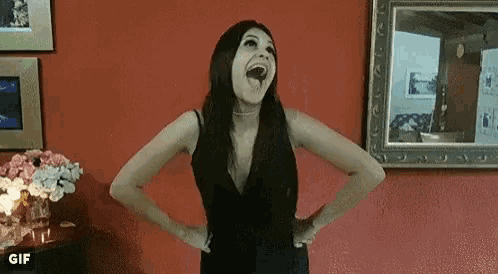 a woman in a black dress is laughing with her mouth open in a living room .