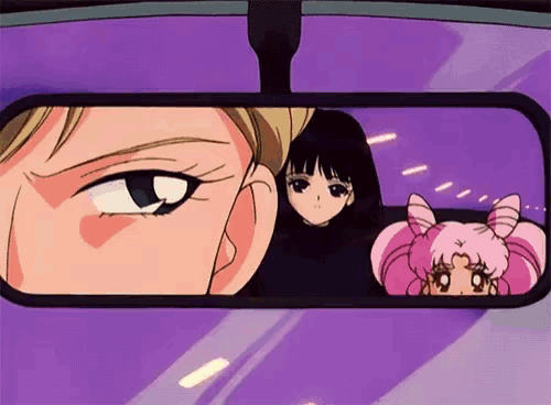 a man and two girls are looking at each other in a car rear view mirror .