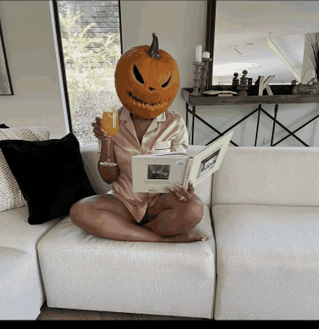 a woman with a pumpkin head is reading a book