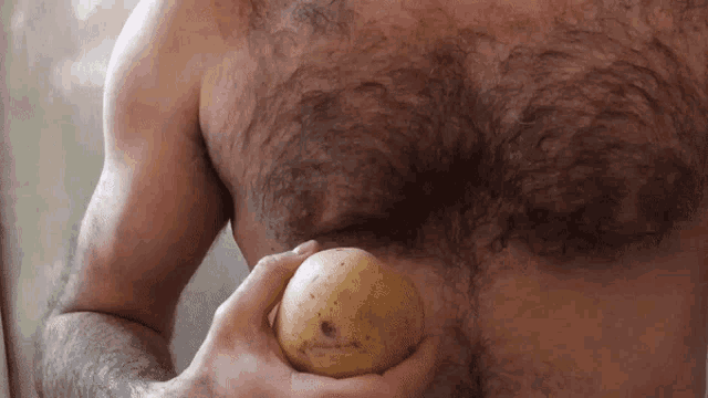 a shirtless man is holding an apple in his hand