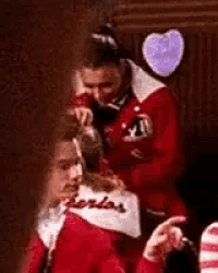 a woman is brushing another woman 's hair in a room with a heart in the background .
