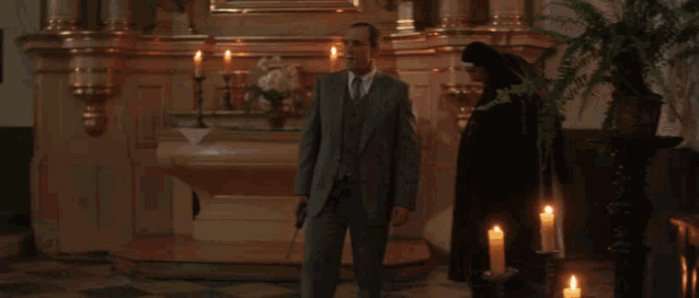 a man in a suit is being shot by a nun