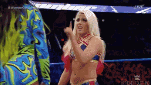 a female wrestler is giving the middle finger to another woman in a wrestling ring .