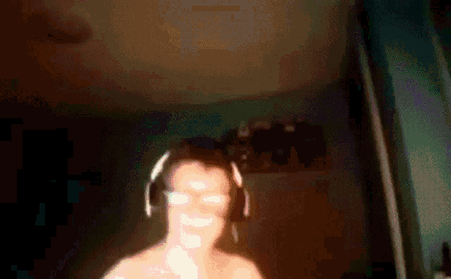 a man wearing headphones and glasses is dancing in a dark room
