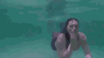 a person is swimming underwater with bubbles coming out of their mouth .