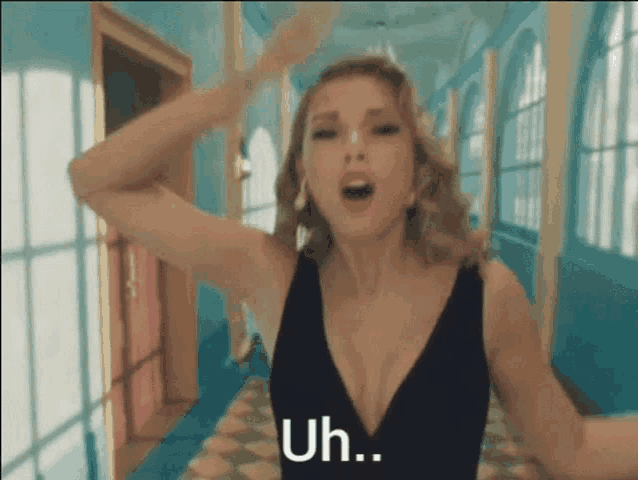 a woman in a black dress is standing in a hallway and saying uh