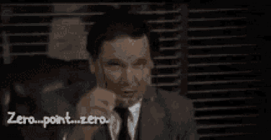 a man in a suit and tie is adjusting his glasses while sitting in front of a window .