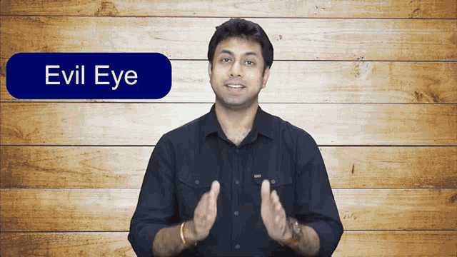 a man stands in front of a wooden wall with a button that says evil eye on it