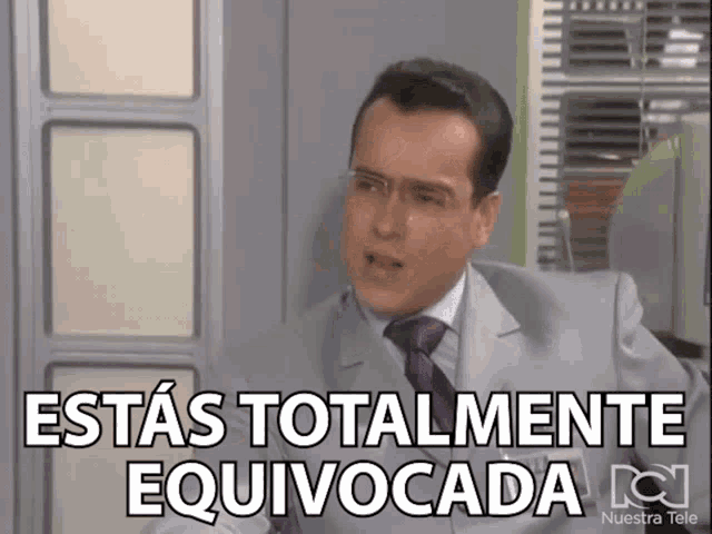 a man in a suit and tie is sitting in front of a sign that says " estas totalmente equivocada "